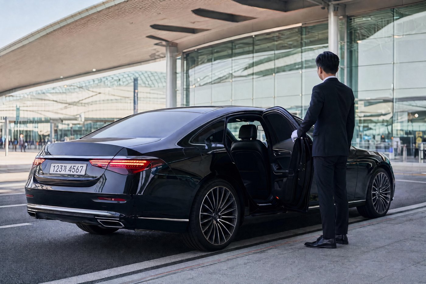 A black executive sedan with a suited chauffeur opening the door outside Incheon Airport
